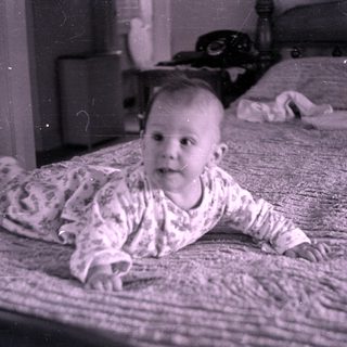 Infant in floral pajamas lying on a bed.
