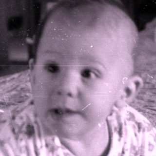 Infant in floral pajamas lying on a bed.