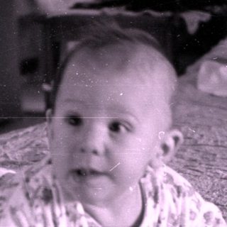 Infant in floral pajamas lying on a bed.