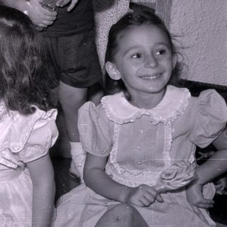 Four children in dress clothes, one holding a lollipop.