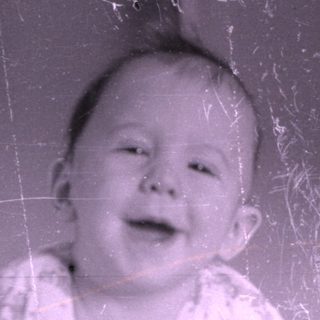 Infant in patterned pajamas lying on a bed.
