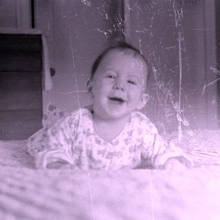 Infant in patterned pajamas lying on a bed.