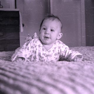 Baby in patterned clothing on a striped blanket.