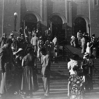 People in formal wear on building steps.