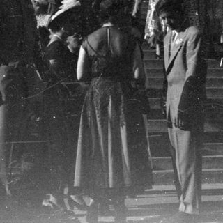 People in formal wear on building steps.
