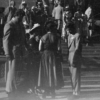 People in formal wear on building steps.