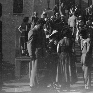 People in formal wear on building steps.
