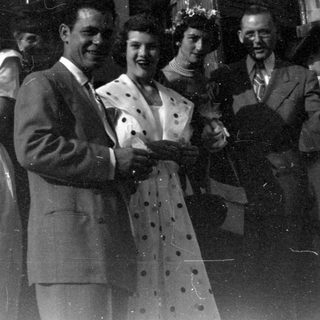 Group of people outside a stone arched building.