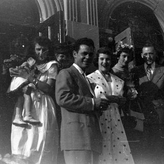 Group of people outside a stone arched building.