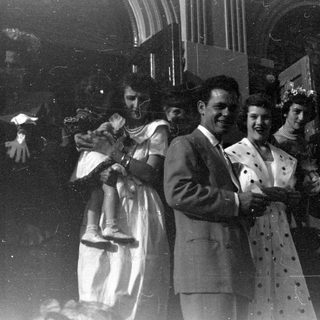 Group of people outside a stone arched building.