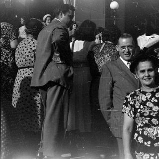 Group of people in formal attire by brick building.