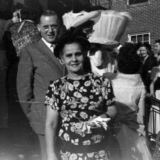 Group of people in formal attire by brick building.