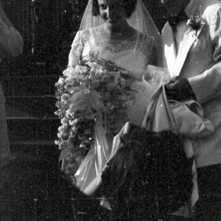 Couple in wedding attire descending stairs with guests.