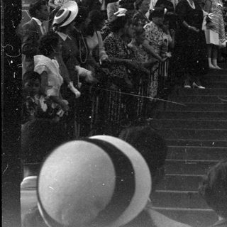 Wedding party descending stone steps of arched building.