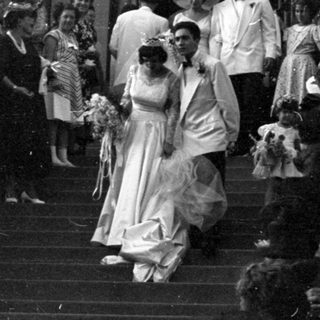 Wedding party descending stone steps of arched building.