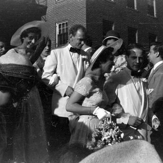 Group in formal attire outside a brick building.