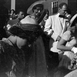 Group in formal attire outside a brick building.