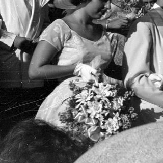 People in formal mid-century attire standing outdoors.