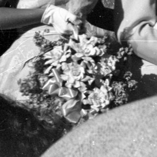 People in formal mid-century attire standing outdoors.