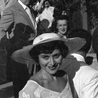 Woman in floral dress and wide hat outdoors.