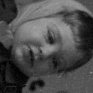 Child climbing out of a white metal crib.