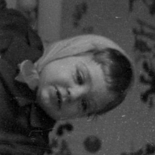 Child climbing out of a white metal crib.