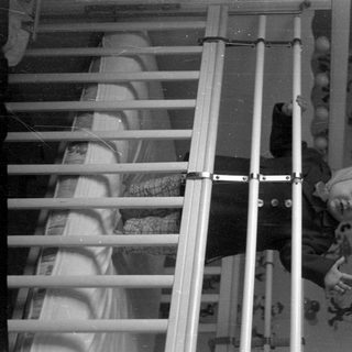 Child climbing out of a white metal crib.