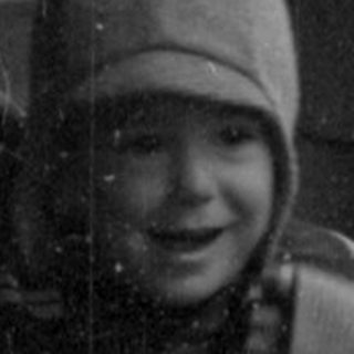 Child and man standing beside a train car.