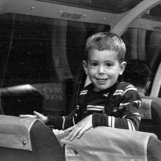 Boy in striped sweater inside a glass-roofed vehicle.