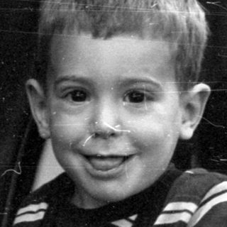 Boy in striped sweater inside a glass-roofed vehicle.