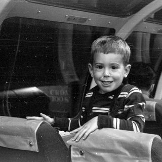 Boy in striped sweater inside a glass-roofed vehicle.
