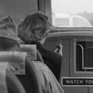 Boy in overalls inside a passenger vehicle.