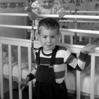 Two young children in a white crib.