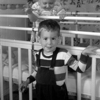 Two young children in a white crib.
