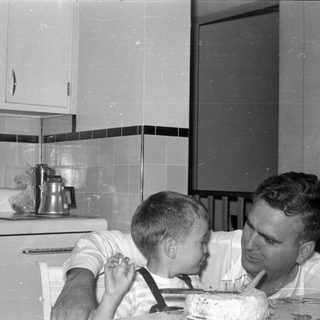 Man and boy with cake in a kitchen.