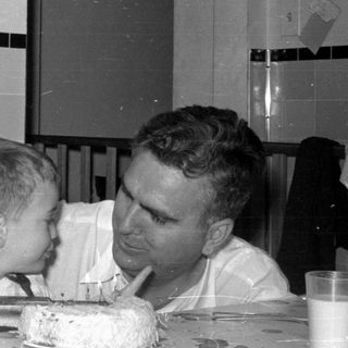 Man and boy with cake in a kitchen.