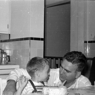 Man and boy with cake in a kitchen.