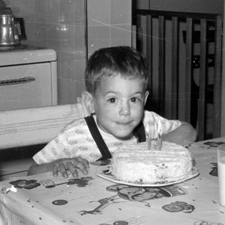 Young boy with birthday cake and milk in kitchen.