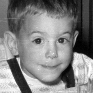 Young boy with birthday cake and milk in kitchen.