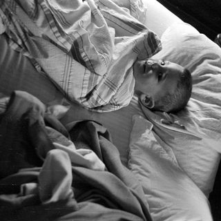 Baby lying on a pillow under striped blankets.