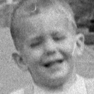 Child in overalls running on a train platform.