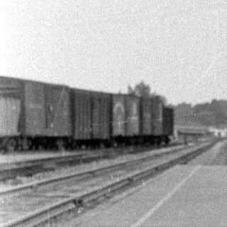 Child in overalls running on a train platform.