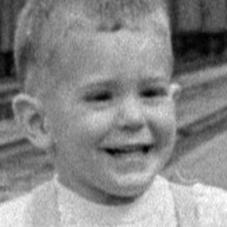 Child in overalls running on a railway platform.