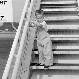 Child on TWA flight stairs at an airfield.