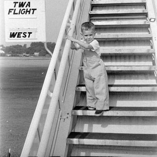 Child on TWA flight stairs at an airfield.