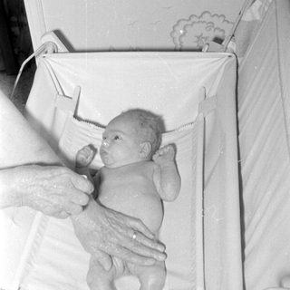Newborn baby lying in a white infant bed.
