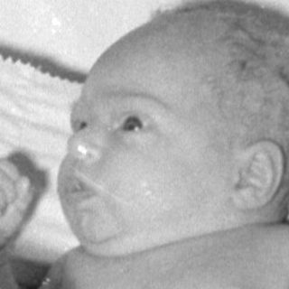 Newborn baby lying in a white infant bed.
