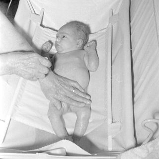 Newborn baby lying in a white infant bed.