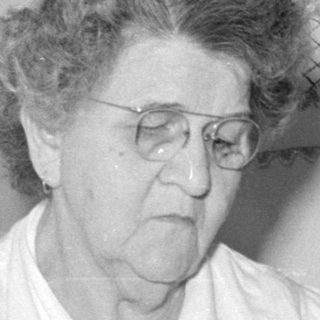 Older woman feeding a baby with a bottle.