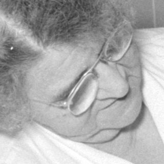 Older woman holding an infant in a kitchen.